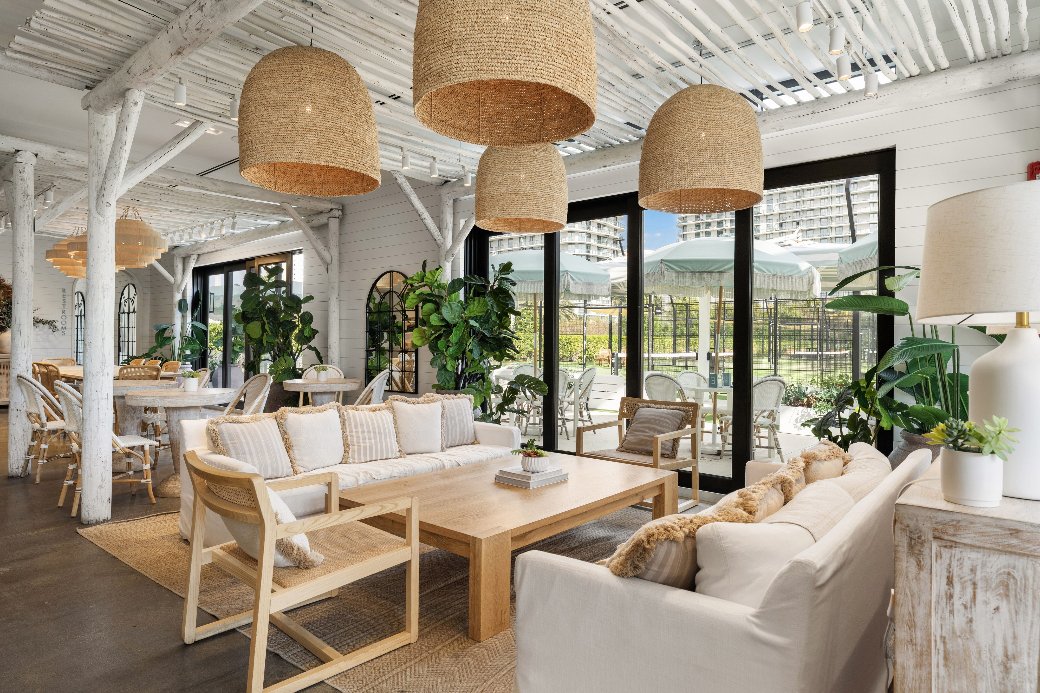 A living room with a white couch, wooden chairs, and a large window.